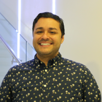 color photograph of a smiling man in a black and gold shirt