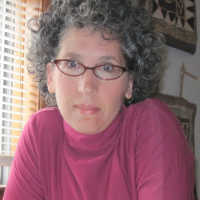 headshot of a woman with glasses sitting at a desk