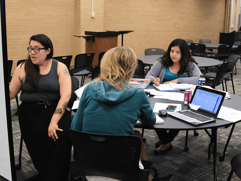 three women sitting at a round study table