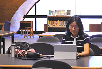 woman sitting at a table looking at her laptop